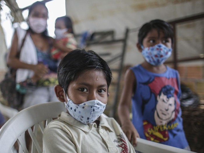 MANAUS, BRAZIL - MAY 21: Indigenous boys wearing protective masks wait for vaccine and testing at Parque das Tribos community, on May 21 2020 in Manaus, Brazil.  Medical teams from Healths Secretary of Manaus area performing vaccination against flu and testing to detect coronavirus (COVID-19) infections on indigenous communities. (Photo by Andre Coelho/Getty Images)