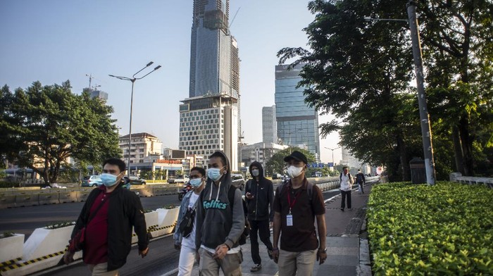 Sejumlah pekerja berjalan di jalur pedestrian Jalan Jenderal Sudirman, Jakarta, Jumat (2/7/2021). Pemerintah akan menerapkan PPKM Darurat di Pulau Jawa dan Bali mulai 3 Juli mendatang, salah satunya mewajibkan menerapkan 