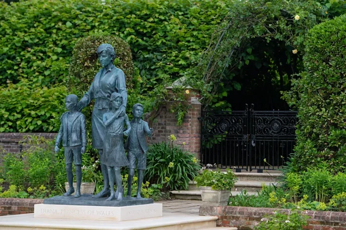 Pangeran Harry dan Pangeran William mengunjungi rumah masa kecil mereka, Istana Kensington. Sebuah patung seorang wanita cantik bersama dua anak terpapang.