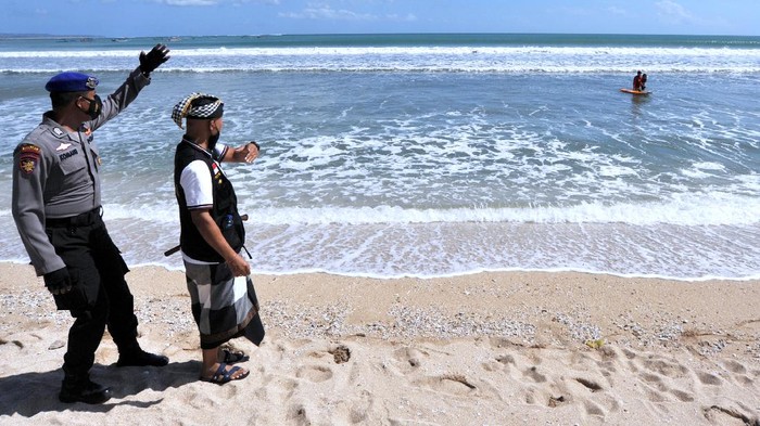 Pecalang atau petugas keamanan adat Bali memasang pembatas jalan untuk menutup pintu masuk kawasan wisata Pantai Kuta di Badung, Bali, Sabtu (3/7/2021). Destinasi pariwisata utama di Pulau Dewata tersebut ditutup sementara selama Pemberlakuan Pembatasan Kegiatan Masyarakat (PPKM) Darurat pada 3-20 Juli 2021 untuk menekan angka penyebaran kasus pandemi COVID-19. ANTARA FOTO/Fikri Yusuf/foc.