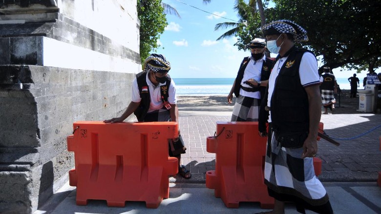 Pecalang atau petugas keamanan adat Bali memasang pembatas jalan untuk menutup pintu masuk kawasan wisata Pantai Kuta di Badung, Bali, Sabtu (3/7/2021). Destinasi pariwisata utama di Pulau Dewata tersebut ditutup sementara selama Pemberlakuan Pembatasan Kegiatan Masyarakat (PPKM) Darurat pada 3-20 Juli 2021 untuk menekan angka penyebaran kasus pandemi COVID-19. ANTARA FOTO/Fikri Yusuf/foc.