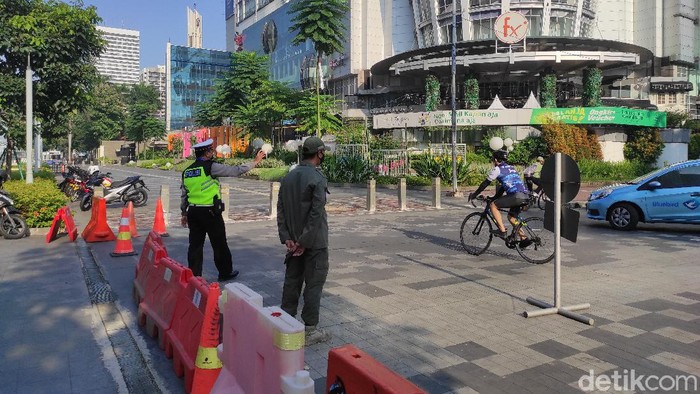 Polisi jalau pesepeda di Jl Jend Sudirman, Senayan, Jakarta, saat PPKM Darurat, 3 Juli 2021. (Azhar Bagas Ramadhan/detikcom)