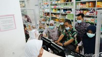 Petugas apotek sibuk melayani pelanggan.