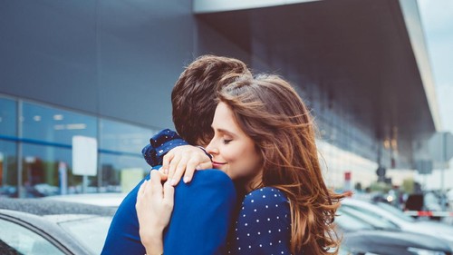 Loving young couple say good bye at airport, man and woman embracing at car parking lot.