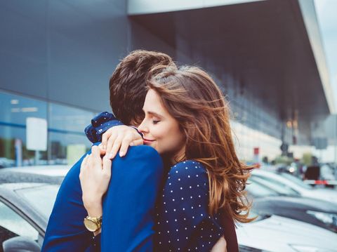 Loving young couple say good bye at airport, man and woman embracing at car parking lot.