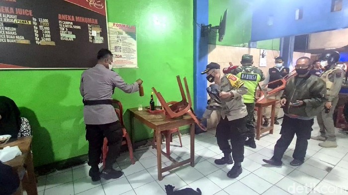 Petugas merapikan kursi penjual bakso di tengah PPKM Darurat.