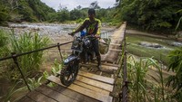 Seorang pengendara melintas di jembatan yang rusak di Desa Datar Ajab, Kabupaten Hulu Sungai Tengah, Kalimantan Selatan.