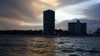 Matahari terbenam di atas bangunan tepi laut, termasuk bangunan kondominium Champlain Towers South yang sebagian runtuh, kanan, di Surfside, Florida.