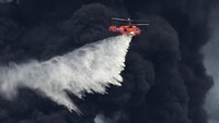 Pekerja darurat masih berjibaku dan helikopter pemadam kebakaran sebelumnya telah menyiramkan air ke area yang sulit dijangkau.