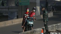 Seorang petugas dari TNI mengarahkan pemotor untuk putar balik.