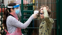 Seorang anggota staf yang mengenakan alat pelindung diri (APD), mengukur suhu anak di sekolah Harris Academys Shortland, London, Inggris. Getty Images/Dan Kitwood