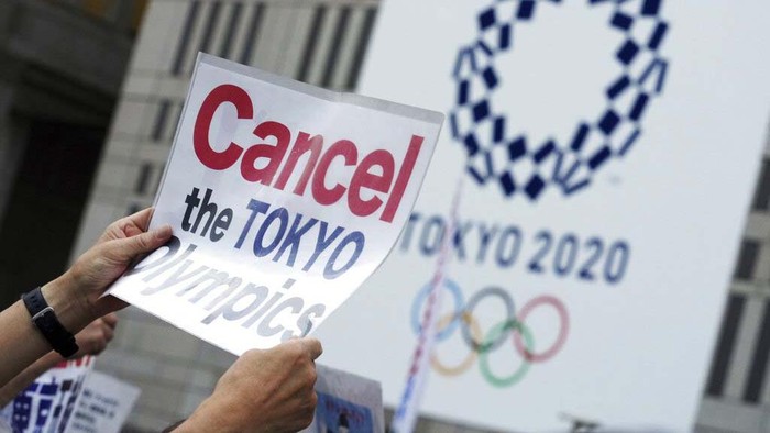 A German athlete, wearing face mask, walks past the Olympic rings display on their arrival at Haneda airport in Tokyo, Thursday, July 1, 2021. The pressure of hosting an Olympics during a still-active pandemic is beginning to show in Japan. The games begin July 23, with organizers determined they will go on, even with a reduced number of spectators or possibly none at all.(Kyodo News via AP)