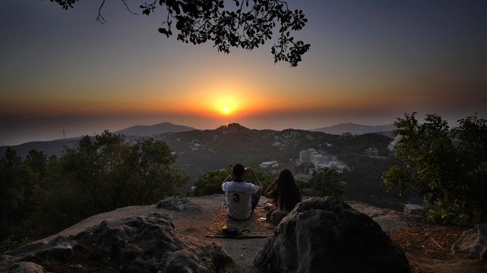 Terperosok dalam Krisis, Lebanon Berharap Cuan dari Turis A young couple enjoy the sunset during a hike trip in Chahtoul village, in the Keserwan district, Mount Lebanon Governorate of Lebanon, Sunday, June 27, 2021. With their dollars trapped in the bank, a lack of functioning credit cards and travel restrictions imposed because of the pandemic, many Lebanese who traditionally vacationed over the summer at regional hotspots are also now turning toward domestic tourism. (AP Photo/Hassan Ammar)
