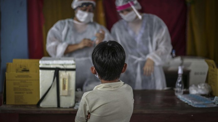 MANAUS, BRAZIL - MAY 21: An indigenous boy observes nurses while waiting for vaccination at Parque das Tribos community, on May 21 2020 in Manaus, Brazil.  Medical teams from Healths Secretary of Manaus area performing vaccination against flu and testing to detect coronavirus (COVID-19) infecctions on indigenous  communities. (Photo by Andre Coelho/Getty Images)