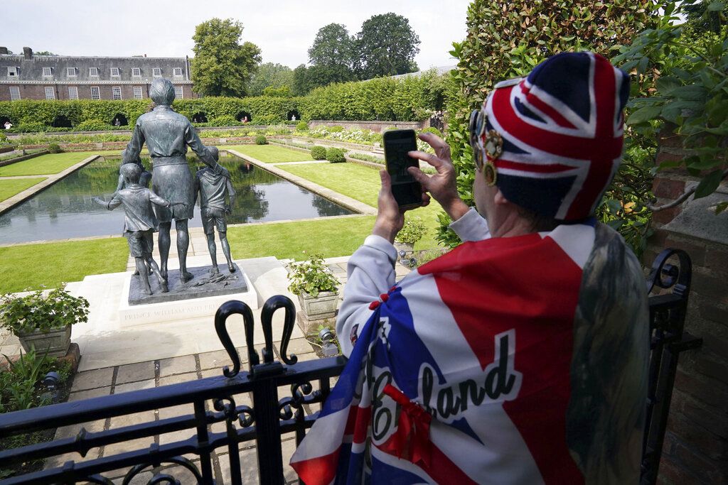 The gates are opened to allow people to see the statue of Diana, Princess of Wales, a day after its unveiling, in the Sunken Garden at Kensington Palace, London, Friday July 2, 2021. The statue, which shows a larger-than-life Diana surrounded by three children, was commissioned by Prince William and Prince Harry in 2017.