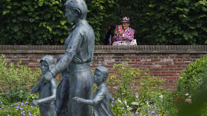 Antusias Warga Inggris Tengok Patung Lady Diana di Istana Kensington The gates are opened to allow people to see the statue of Diana, Princess of Wales, a day after its unveiling, in the Sunken Garden at Kensington Palace, London, Friday July 2, 2021. The statue, which shows a larger-than-life Diana surrounded by three children, was commissioned by Prince William and Prince Harry in 2017.