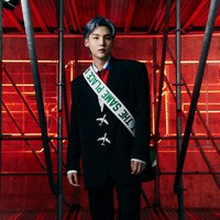 RM kemudian melirik ke arah Suga BTS yang mengenakan coat hitam serupa, dengan detail kancing berbentuk pesawat. Pemilik nama asli Kim Yoongi itu memakai tas hijau dengan bandouliére bertuliskan ‘At the Same Place At the Same Time’. Foto: dok. Louis Vuitton