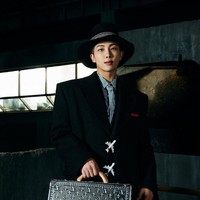 Jimin kemudian menoleh ke arah RM BTS, yang berjalanan menuruni anak tangga. Leader grup BTS itu tampil mengenakan coat panjang berwarna hitam sambil menjinjing tas silver Valise Cotteville 40 dengan logo Louis Vuitton. Foto: dok. Louis Vuitton