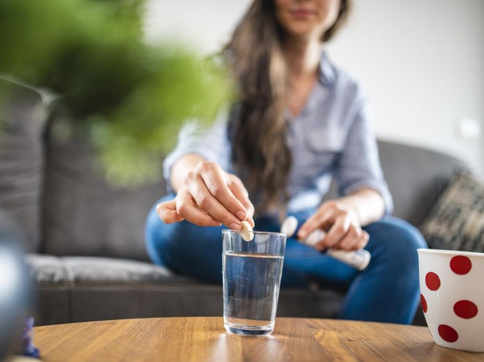 Ilustrasi Vitamin C Close up of a Caucasian Woman in her 20s dissolving a Effervescent Tablet in water