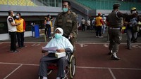 Petugas membantu lansia menuju tempat vaksin.