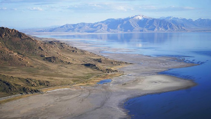 Robert Atkinson flies over the Great Salt Lake during a tandem paramotoring flight on June 18, 2021, near Salt Lake City. A resort long since closed once drew sunbathers who would float like corks in the extra salty waters. Picnic tables once a quick stroll from the shore are now a 10-minute walk away. Atkinson, 91, remembers that resort and the feeling of weightlessness in the water. When he returned this year to fly over the lake in a motorized paraglider, he found it changed. 