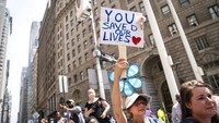 Warga pun sangat antusias menyaksikan pawai dengan memperlihatkan poster yang berisi ucapan terima kasih kepada petugas di garda terdepan. AP Photo/John Minchillo.