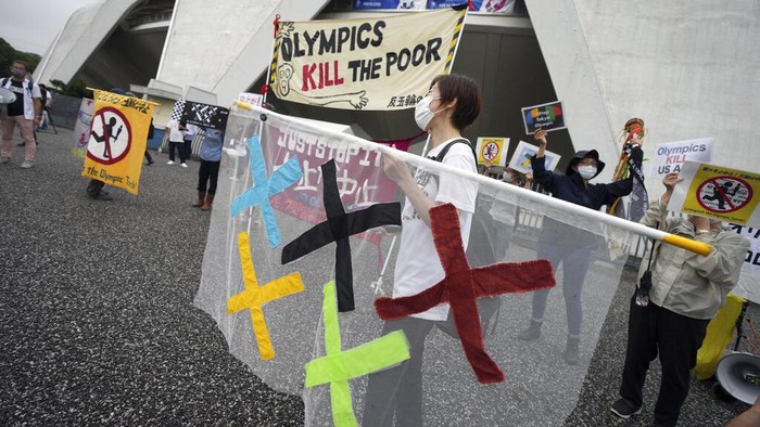 People look at the unveiling ceremony for Olympic Flame of the Tokyo 2020 Olympic torch relay from a pedestrian bridge near Komazawa Olympic Park, Friday, July 9, 2021, in Tokyo. (AP Photo/Eugene Hoshiko)