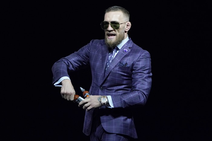 Conor McGregor, right, kicks at Dustin Poirier, left, as Dana White, UFC President, holds them apart during a news conference for a UFC 264 mixed martial arts bout Thursday, July 8, 2021, in Las Vegas. (AP Photo/John Locher)