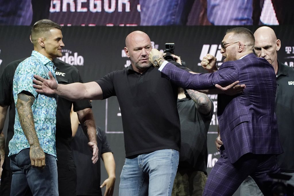 Conor McGregor, right, kicks at Dustin Poirier, left, as Dana White, UFC President, holds them apart during a news conference for a UFC 264 mixed martial arts bout Thursday, July 8, 2021, in Las Vegas. (AP Photo/John Locher)