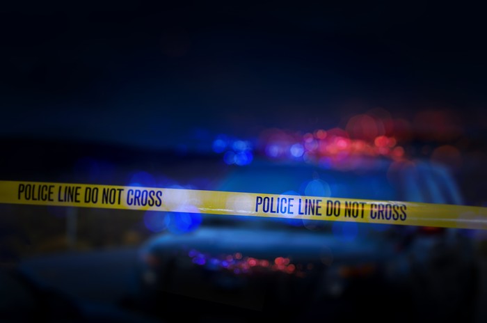 Yellow crime scene do not cross barrier tape in front of defocused background. Horizontal composition with selective focus and copy space.