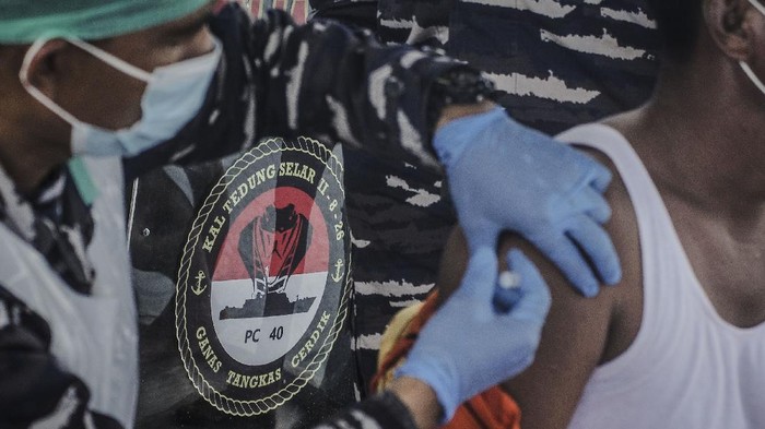 Anggota TNI AL menyuntikkan vaksin COVID-19 kepada seorang nelayan di geladak KAL Tedung Selar II-​8-26 di perairan Pulau Kinabuhutan, Minahasa Utara, Sulawesi Utara.