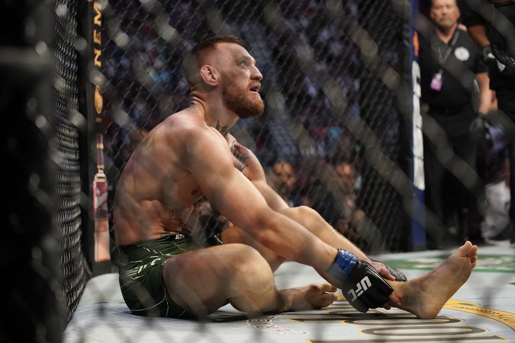 Connor McGregor memegang pergelangan kaki kirinya saat bertarung dengan Dustin Bory selama Kejuaraan Seni Bela Diri Campuran Ringan UFC 264 pada Sabtu 10 Juli 2021 di Las Vegas.  (Foto AP / John Locher)