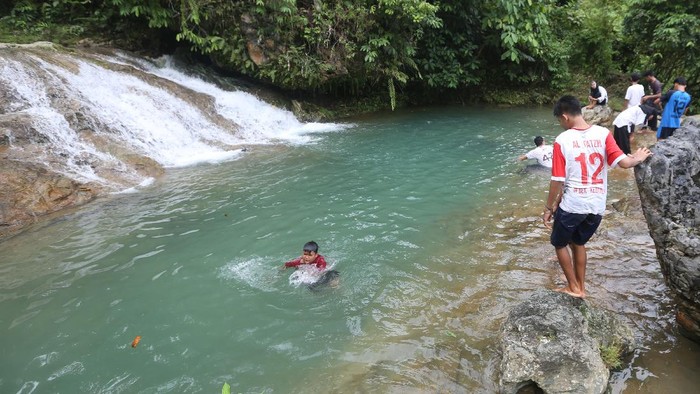 Wisatawan mengunjungi objek wisata Air Terjun Tingkat Tujuh di Tapaktuan, Aceh Selatan, Aceh, Minggu (11/7/2021). Air terjun yang memiliki tujuh tingkat tersebut masih menjadi lokasi wisata yang menerapkan protokol kesehatan secara ketat sebagai upaya pencegahan dan penularan COVID-19. ANTARA FOTO/Irwansyah Putra/wsj.