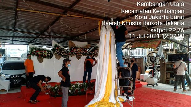 Satpol PP bongkar dekorasi resepsi pernikahan warga di Kembangan Utara, Jakarta Barat, Minggu (11/7/2021).
