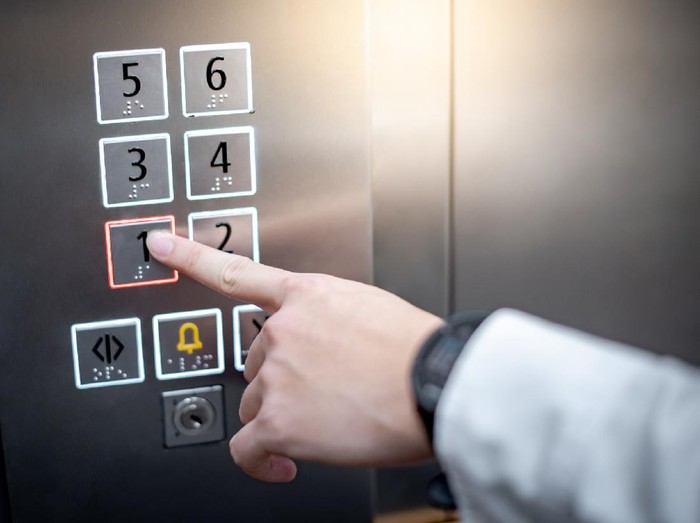 Male forefinger (index finger) pressing on the first floor button or floor number one in elevator (lift). Mechanical engineering concept