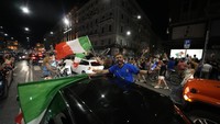 Kembang api menerangi langit, mobil-mobil membunyikan klakson tanpa henti dan penggemar gembira yang mengibarkan bendera Italia tumpah ruah dari Piazza del Popolo tempat mereka menonton pertandingan di layar lebar. Foto: AP/Luca Bruno