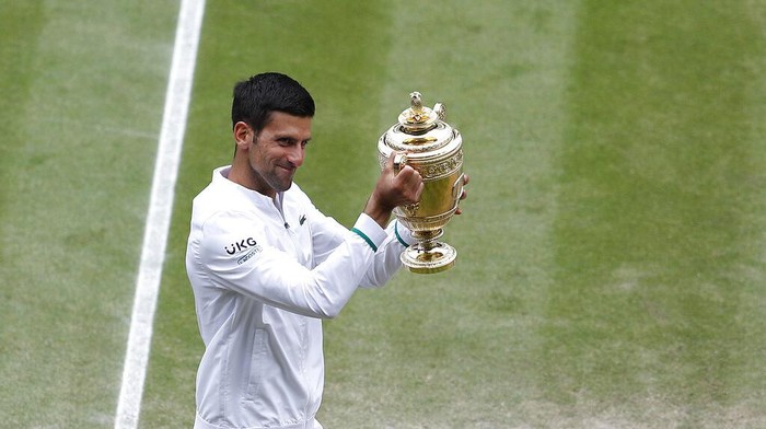 Serbias Novak Djokovic shows off the winners trophy to the crowd as he walks around Centre Court after defeating Italys Matteo Berrettini in the mens singles final on day thirteen of the Wimbledon Tennis Championships in London, Sunday, July 11, 2021. (Pete Nichols/Pool Via AP)