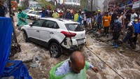 Sejumlah warga mencoba menyelamatkan mobil yang rusak diterjang banjir bandang di Bhagsunag, India, Senin (12/7/2021).