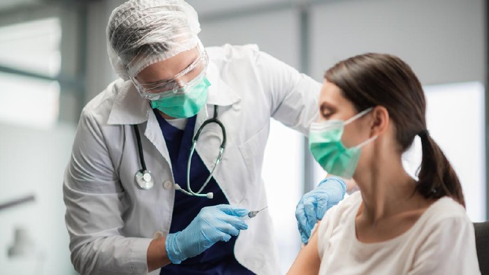 The covid-19 vaccine is injected into a young womans hand.