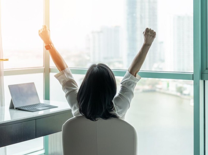 Ilustrasi wanita sukses Business achievement concept with happy businesswoman relaxing in office or hotel room, resting and raising fists with ambition looking forward to city building urban scene through glass window
