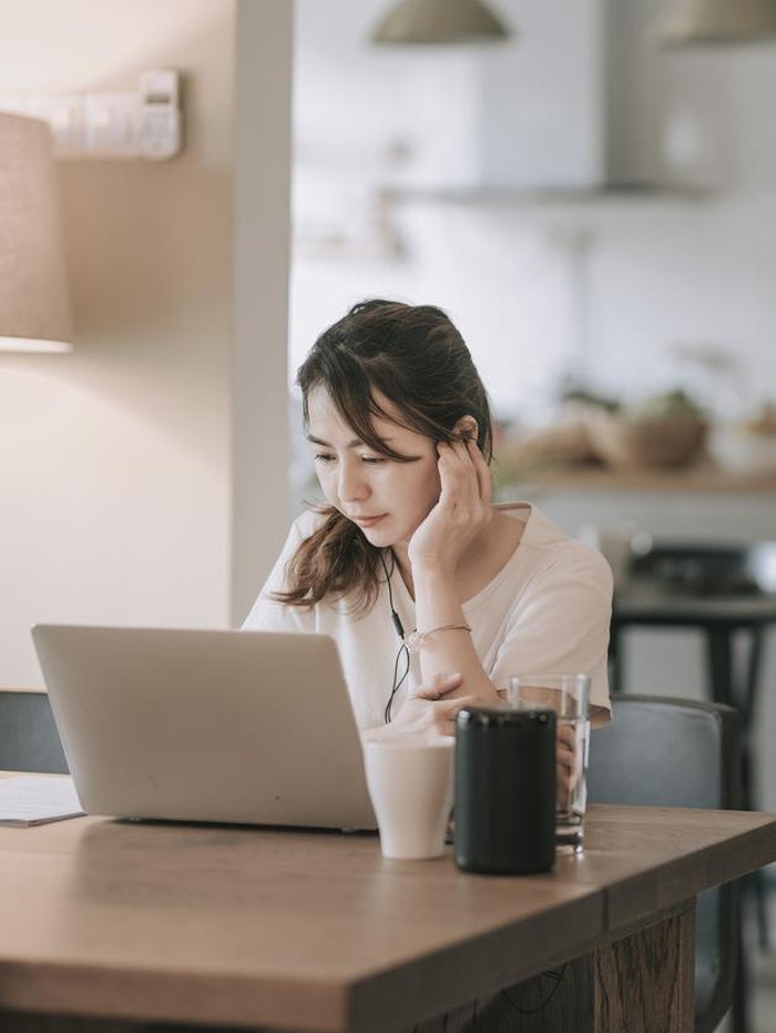 an asian chinese mid adult woman working in dining room typing using her laptop