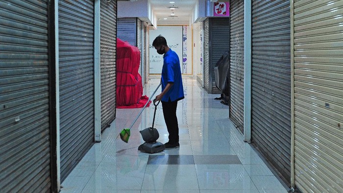 Pengunjung menuruni eskalator di samping deretan toko yang sudah tutup di pusat berbelanjaan modern, Jambi, Senin (12/7/2021). Pemerintah Kota Jambi membatasi jam operasional pusat perbelanjaan atau perdagangan di daerah itu sampai pukul 17.00 WIB dengan pembatasan kapasitas pengunjung 25 persen dan penerapan protokol kesehatan untuk mengendalikan penyebaran COVID-19. ANTARA FOTO/Wahdi Septiawan/foc.
