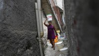 Seorang wanita membawa ember berisi air yang dibelinya dari tetangga seharga dua puluh sen dolar.