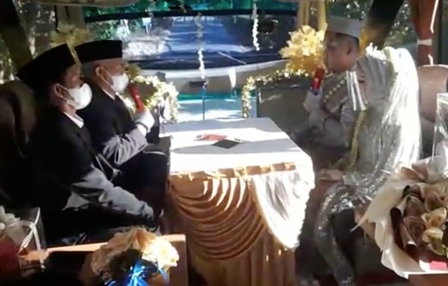 Inilah pengantin yang viral menikah di dalam bus yang berjalan saat PPKM darurat. Mereka mengungkapkan alasan akad nikah di bus. “Sebenarnya nikah kita konsepnya normal, sudah mendapat izin, mau resepsi. Tapi ada PPKM (darurat), terus dibatalkan. Terus kami putar pikiran untuk nikah di rumah, cuma ijab saja, tidak ada resepsi untuk meminimalisir kerumunan. Tapi kalau di desa itu kan meskipun tidak ada acara, ijab saja pasti banyak yang datang,” kata Angga saat dikonfirmasi Wolipop melalui telepon selulernya, Rabu (14/7/2021). Foto: Dok. Pribadi Titin Rachmatul Ummah dan Angga Hayu Joko Siswoyo