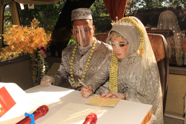 Angga menyatakan selama acara pernikahan, mereka tetap menerapkan protokol kesehatan. Bus yang semula berkapasitas 50, didekorasi untuk nikahan sehingga tinggal berkapasitas 35. “Tetapi kemarin yang ikut di (prosesi nikahan) dalam bus cuma 12 orang. Karena kita mentaati peraturan pemerintah, harus Prokes, jaga jarak. Kalau di jalan ada pemeriksaan, kita aman, kita mentaati protokol kesehatan,” tandasnya. Foto: Dok. Pribadi Titin Rachmatul Ummah dan Angga Hayu Joko Siswoyo