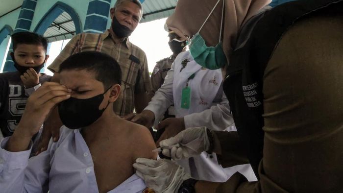 Pelajar di Berbagai Daerah Jalani Vaksinasi Massal Petugas kesehatan menyuntikkan vaksin COVID-19 kepada seorang pelajar remaja di Lhokseumawe, Aceh, Senin (12/7/2021). Vaksinasi dosis pertama dengan target vaksinasi 100 remaja dari usia 12-17 tahun tersebut dalam rangka percepatan vaksinasi sekaligus mendukung program satu juta vaksin COVID-19 per hari. ANTARA FOTO/Rahmad/aww.