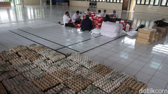 Sejumlah petugas tengah menyiapkan bantuan makanan untuk warga isoman.