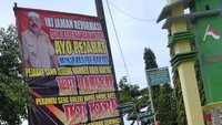 Selain bertuliskan kata-kata yang cenderung kasar, baliho ini juga dipasangi foto sang kades berseragam dengan memasang masker di dahi.