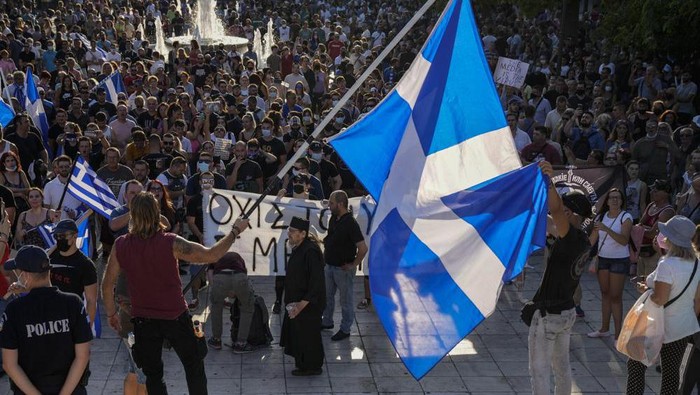 Ribuan warga Yunani ikut unjuk rasa menentang vaksinasi Corona Anti-vaccine protester hold Greek flags during demonstration at Syntagma square, central Athens, on Wednesday, July 14, 2021. Some thousands of anti-vaccine demonstrators gathered in Greece's two largest cities Wednesday over plans to make the vaccine available to children from age 15. Just over 50% of Greeks and country residents have received at least one dose of the COVID-19 vaccine.(AP Photo/Petros Giannakouris)