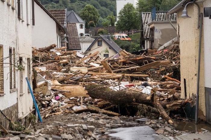 GERMANY-WEATHER-FLOODS A man walks past a car immersed in debris after floods caused major damage in Hagen, western Germany, on July 15, 2021. - Heavy rains and floods lashing western Europe have killed at least 42 people in Germany and left many more missing, as rising waters led several houses to collapse. (Photo by INA FASSBENDER / AFP)